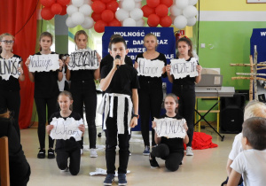 Uczniowie klasy VI a prezentują hasła niepodległościowe.