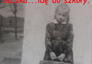 Zdjęcie uczennicy Krystyny Hamery (Jędrzejek) na tle budynku domu kolejowego wraz z opisem - Fartuszek z biały kołnierzykiem, tarcza na rękawie, teczka... idę do szkoły.