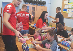 Kibice rozdają uczniom upominki