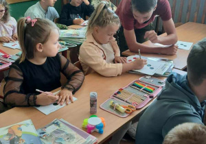 Ósmoklasista pomaga młodszej koleżance.