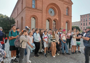 Uczniowie poznają historię Ratusza Nowomiejskiego.