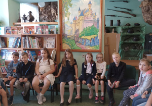 Uczniowie słuchają książki czytanej przez Panią Bibliotekarkę