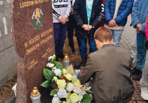 Uczeń składa znicz ku pamięci zmarłych strażaków